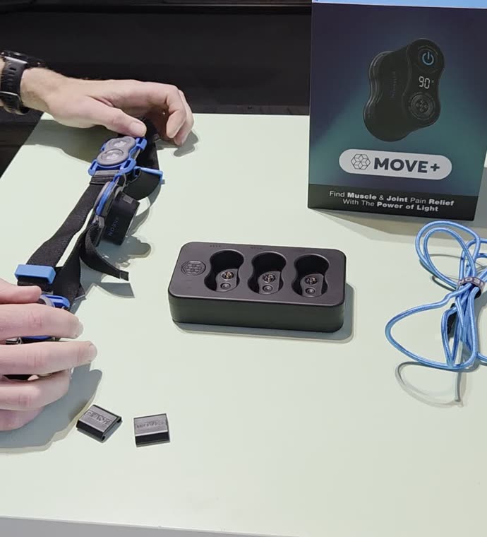 Kineon Move+ med rem, laddstation och blå USB-kabel på ett bord