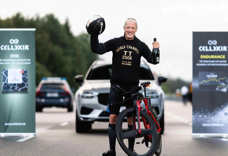 Jonas Bohr poserar med sin cykel och skumpa i handen